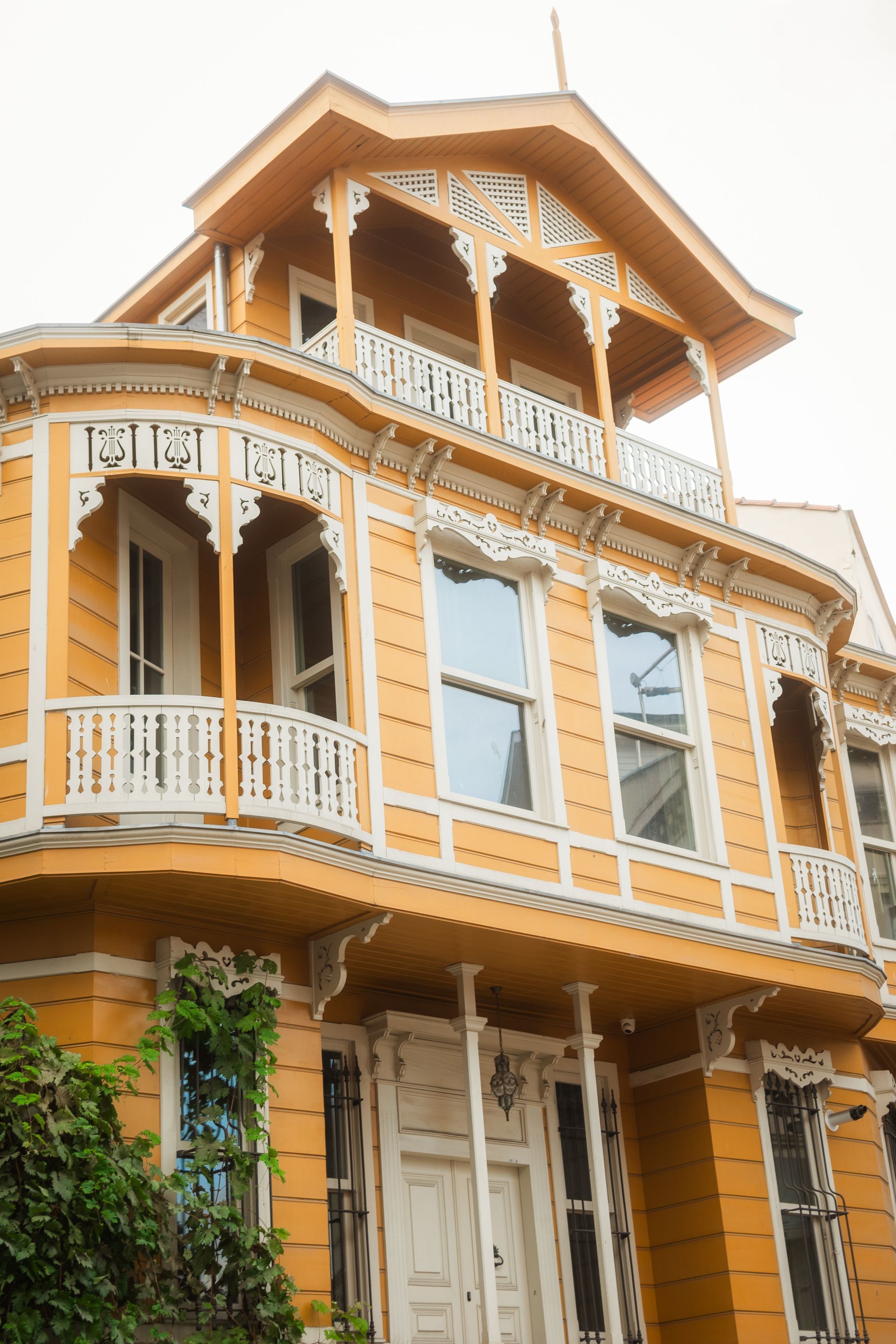 Elegant yellow Victorian house with detailed white trim and classic architecture captured in a low angle shot.